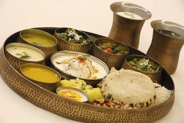 A traditional Indian meal with various dishes and a flatbread, served on a decorative tray.