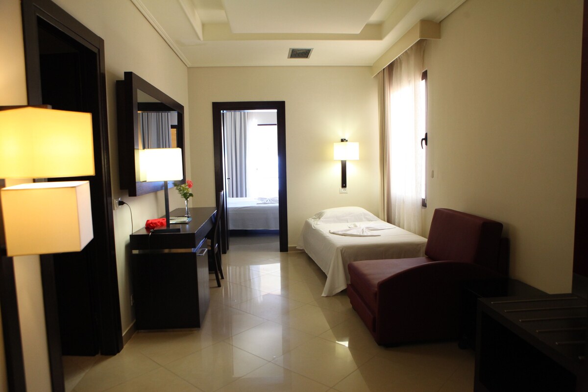 Una habitación de hotel con cama, escritorio, silla, lámpara y espejo.