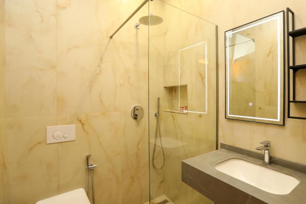 A bathroom with a glass-enclosed shower, a sink with a mirror, and a toilet.