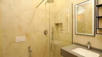 A bathroom with a glass-enclosed shower, a sink with a mirror, and a toilet.