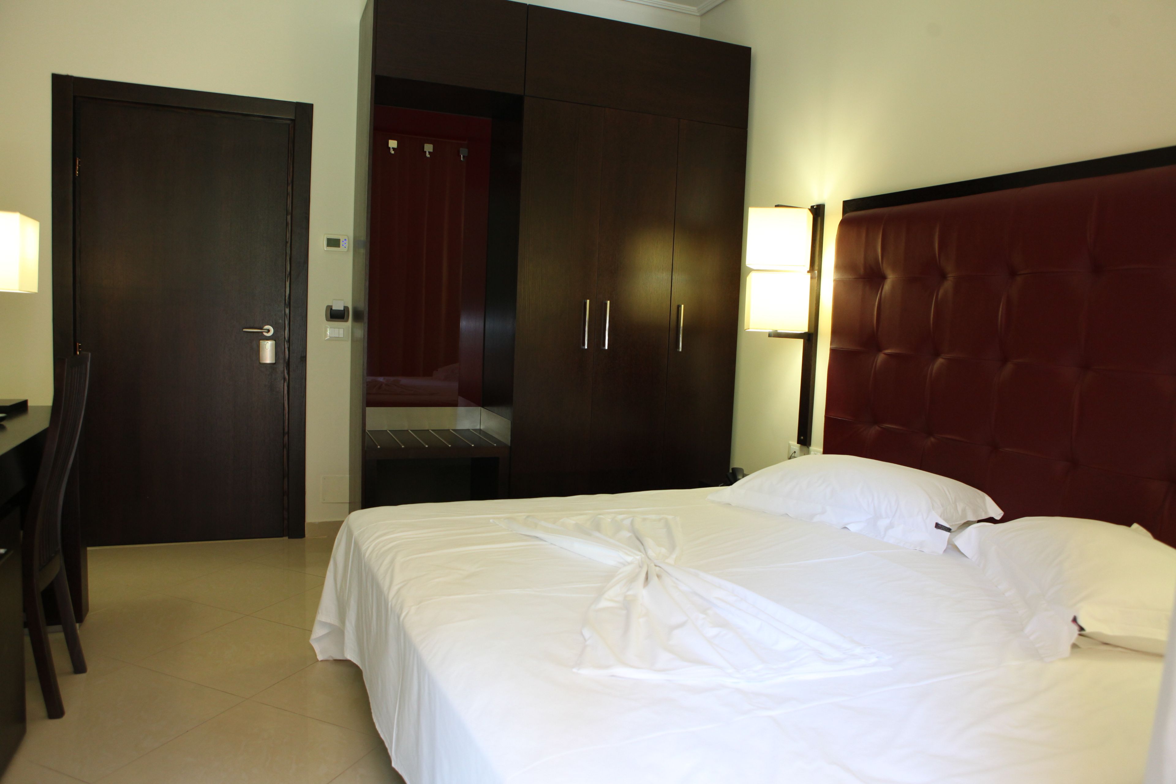 A hotel room with a bed, a desk, and a wardrobe.