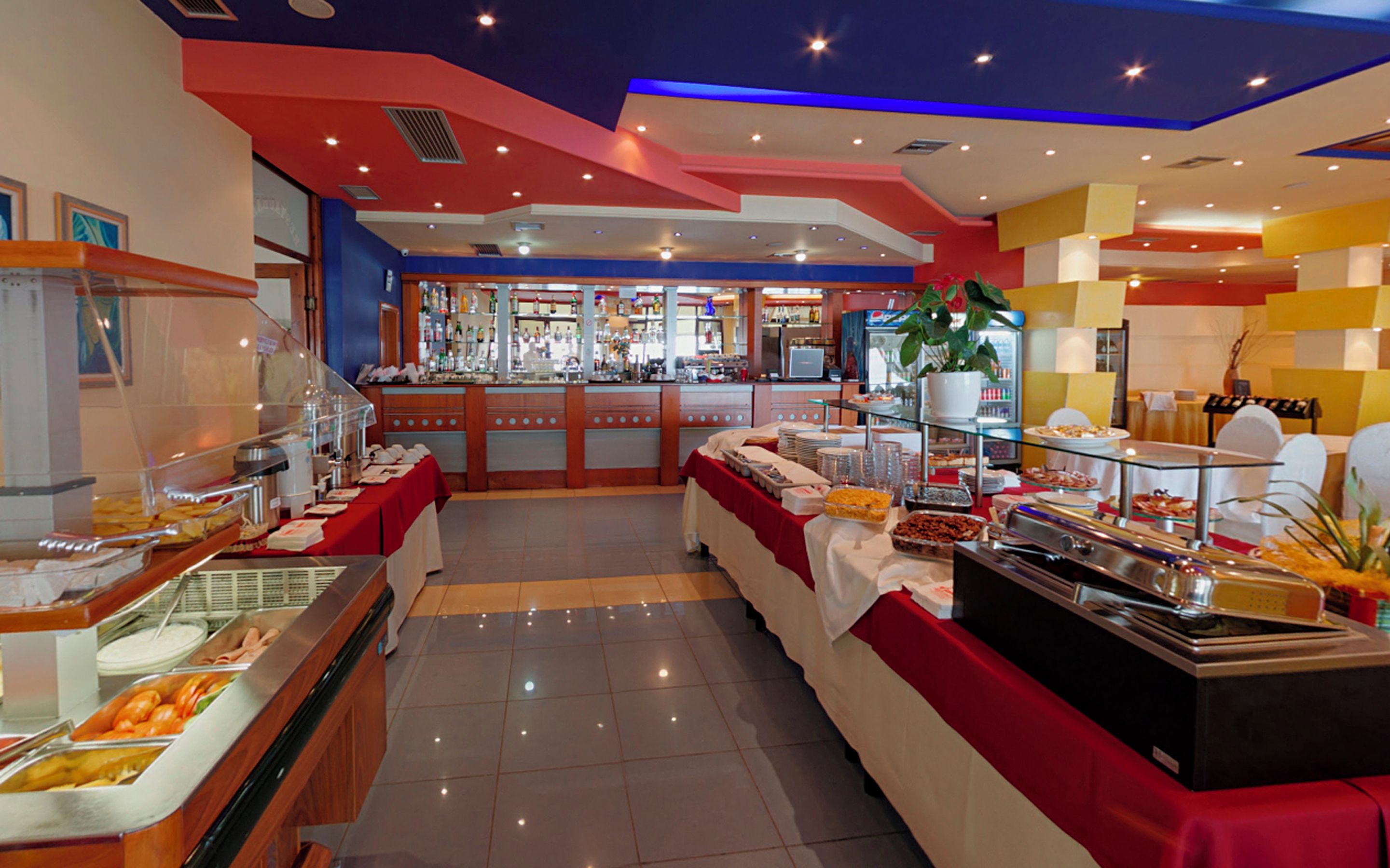 A buffet area with various food stations, a bar, and a seating area with tables and chairs.