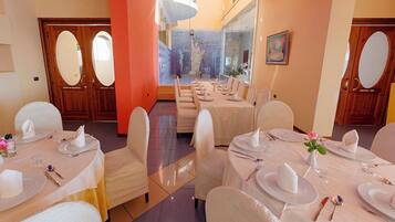 Área de jantar com mesas postas, cadeiras e vista da Estátua da Liberdade através de um painel de vidro.