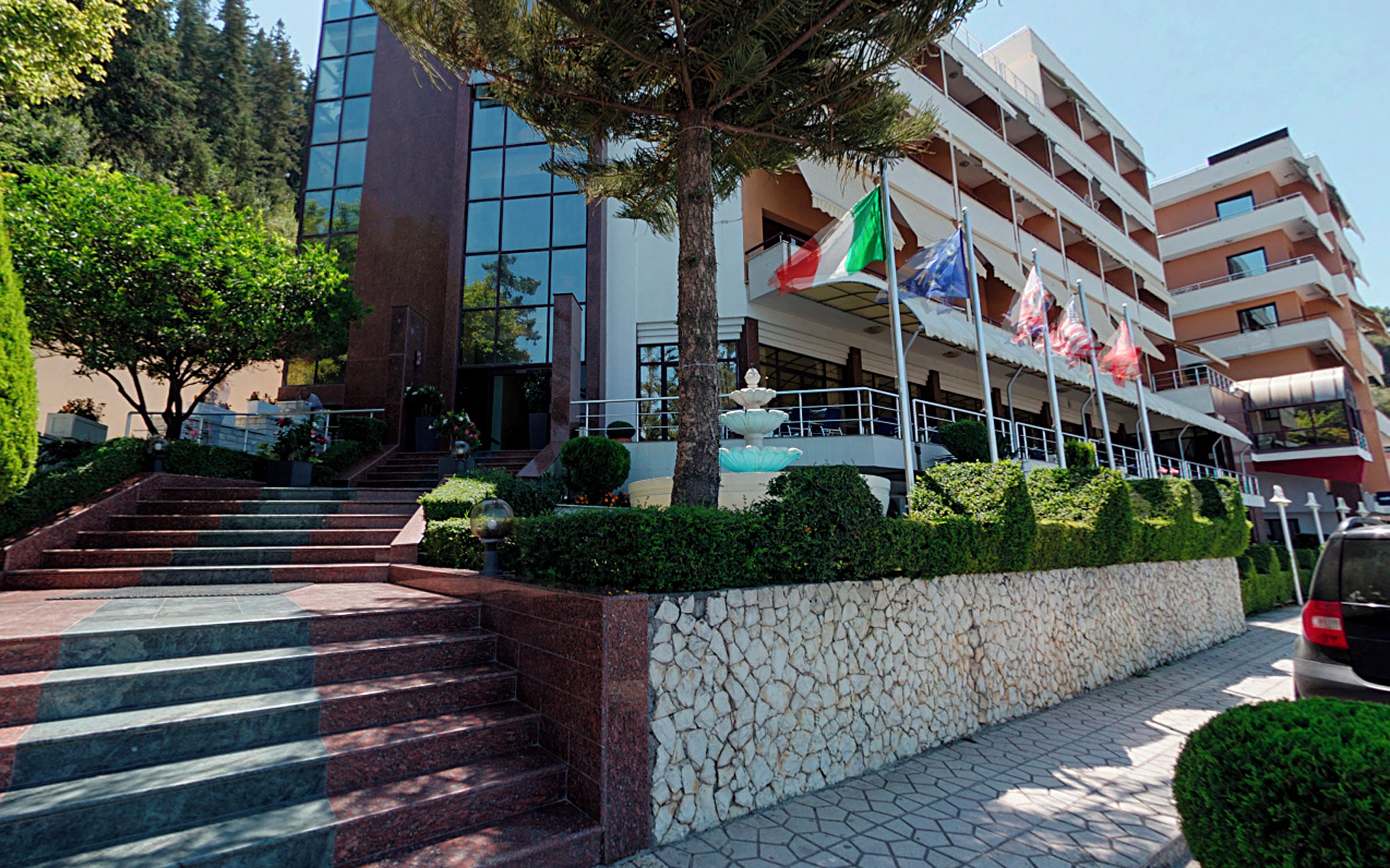 A hotel with a stone facade, a fountain, and multiple balconies.