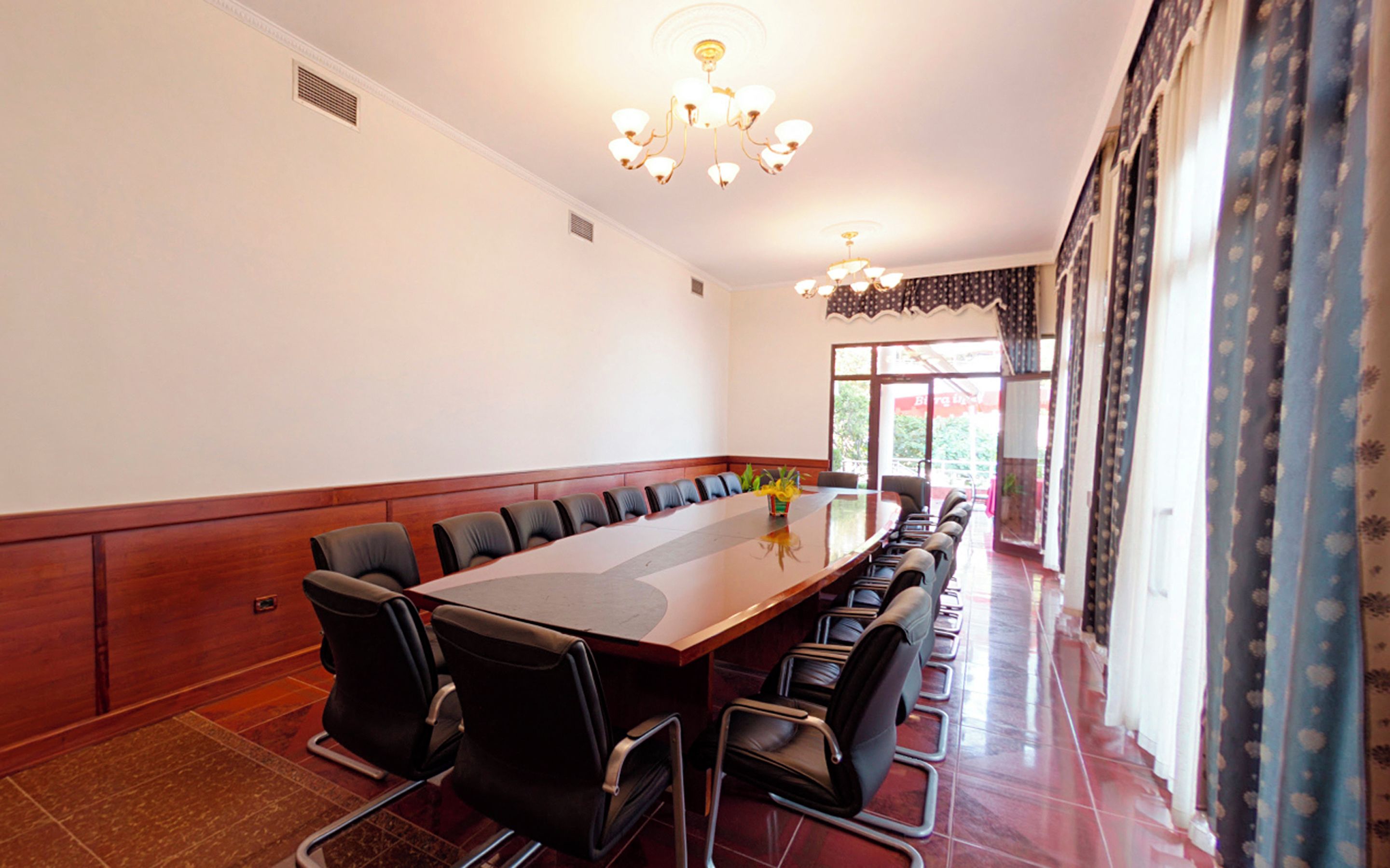 A conference room with a long table, chairs, and a chandelier.