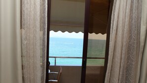 A balcony with a view of the sea, a chair, and a table.