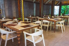A restaurant with multiple tables and chairs, some with placemats. - Grand Barong Resort (Bali)