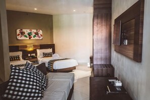 A hotel room with two beds, a sofa, a TV, and a wall-mounted TV. - Grand Barong Resort (Bali)