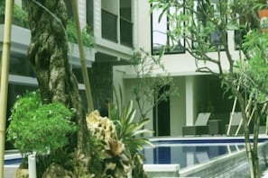 A modern building with a pool, surrounded by various plants and trees. - Grand Barong Resort (Bali)