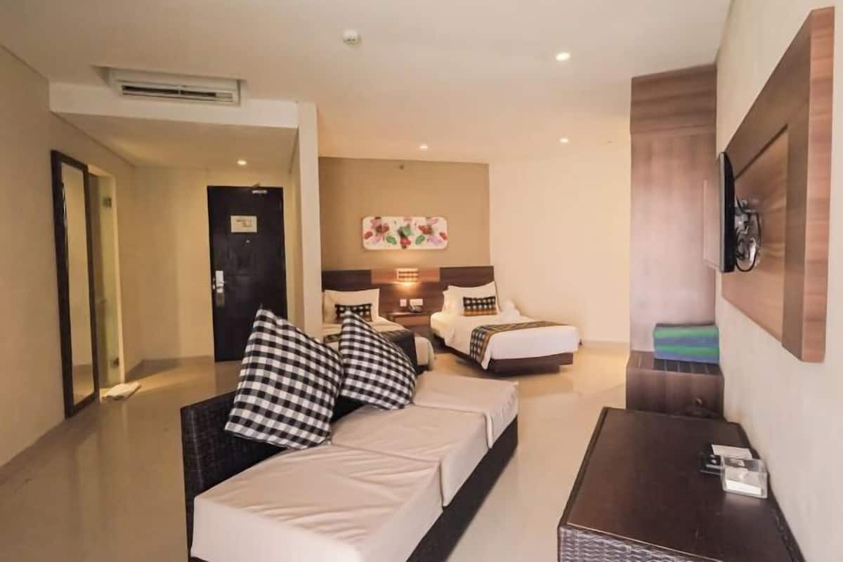A hotel room with a bed, a sofa, a TV, and a desk.