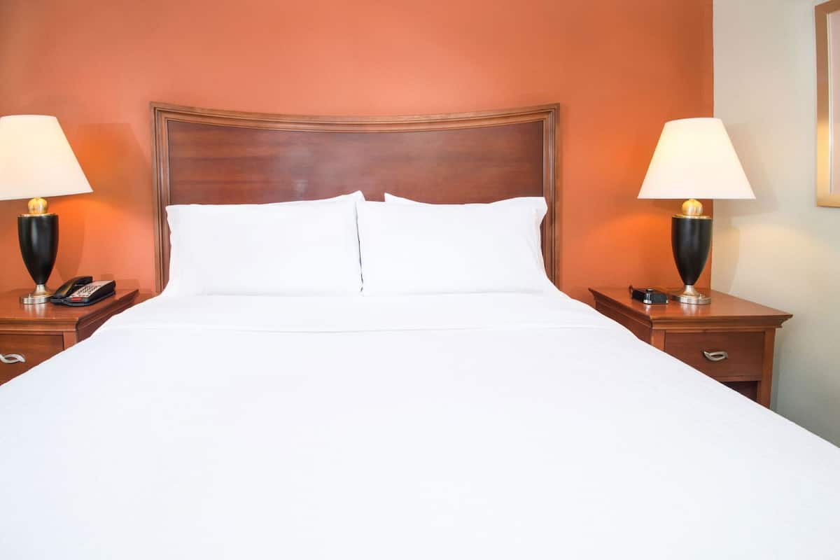 A hotel room with a large bed, two bedside tables with lamps, and a wooden headboard.