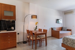 A compact room with a kitchenette, a dining table with chairs, a sofa, and a bed. - Delfina Boutique (Apokoronas)