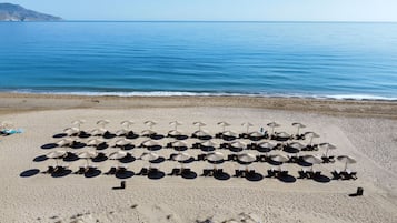 Ein Strand mit Reihen von Liegestühlen und Sonnenschirmen.