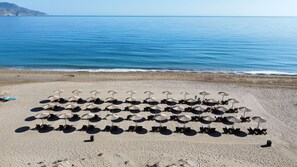 A beach with rows of sun loungers and umbrellas.