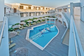 A modern hotel with a central swimming pool, sun loungers, and a covered seating area. - Delfina Boutique (Apokoronas)