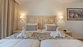 Une chambre d’hôtel avec un grand lit, deux tables de chevet, une tête de lit ornée d’un panneau décoratif, des lampes fixées au mur et un tableau accroché au mur.