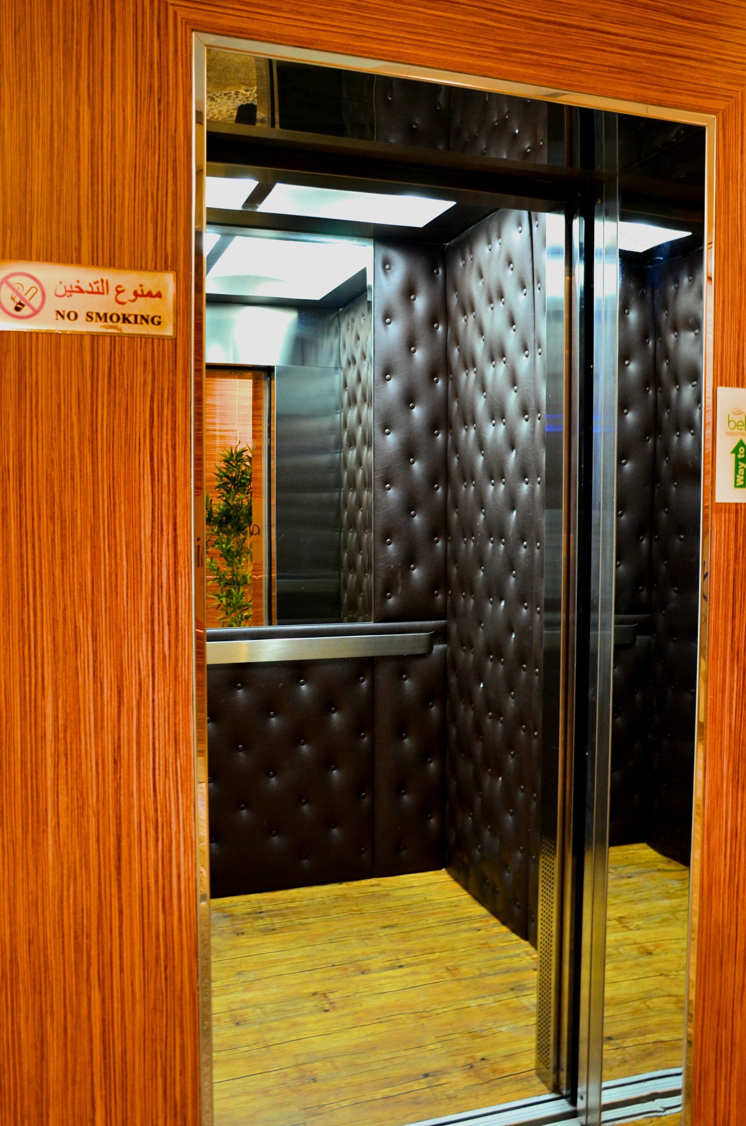 Interior de elevador com placa de 'Proibido Fumar', painéis de madeira e design de parede com textura.