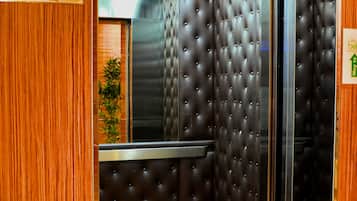 Interior de elevador com placa de 'Proibido Fumar', painéis de madeira e design de parede com textura.