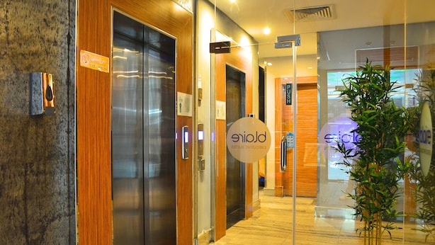 Entrada de hotel con diseño moderno, con puerta de vidrio, panel de madera y un letrero que indica zona para fumadores.