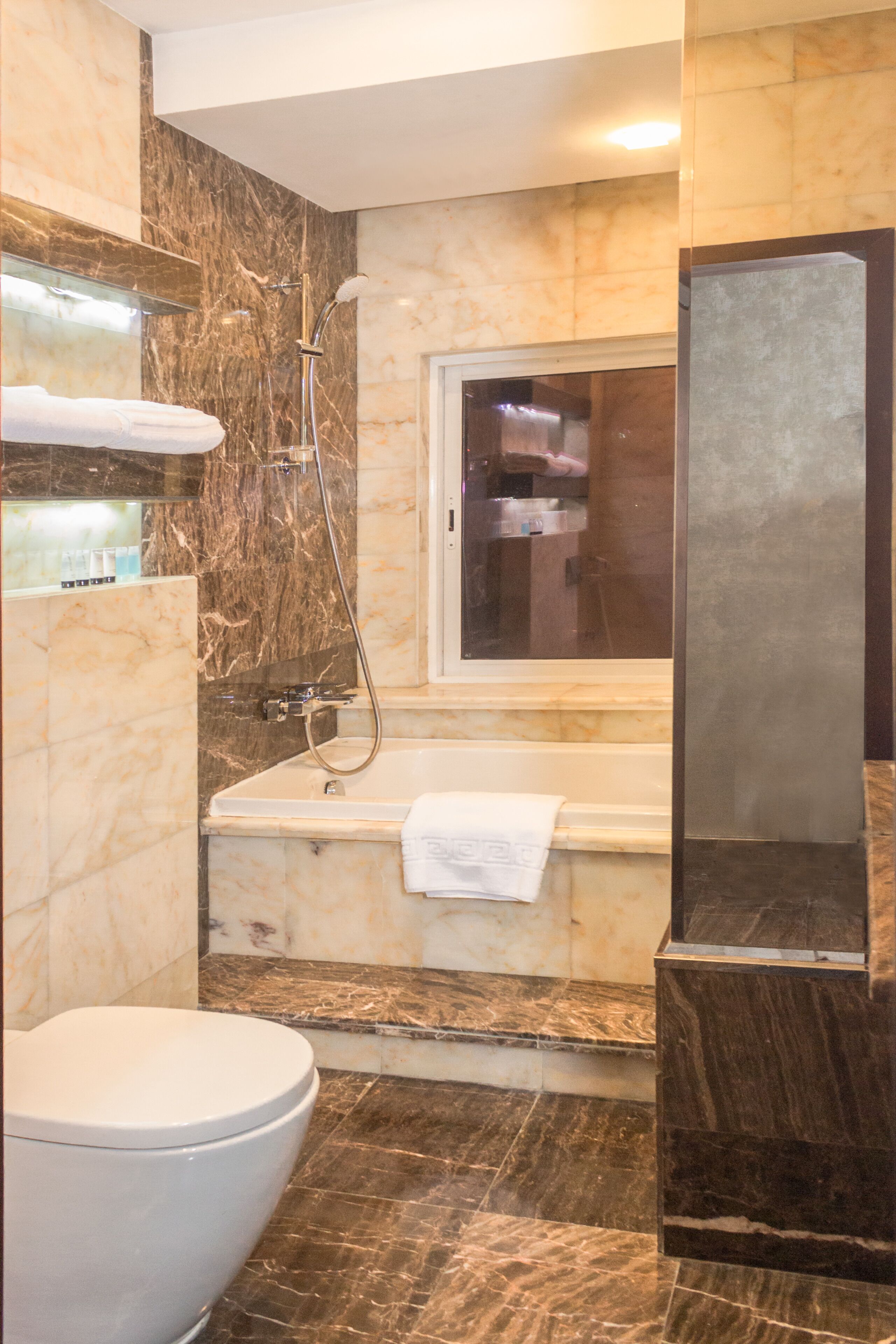 Un baño moderno con suelo de mármol, bañera, inodoro y zona de ducha.