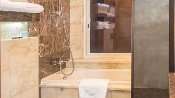 Un baño moderno con suelo de mármol, bañera, inodoro y zona de ducha.