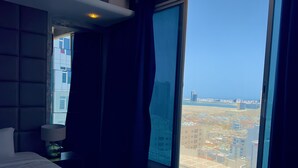 Una habitación de hotel con un ventanal grande, una cama y una mesita de noche.