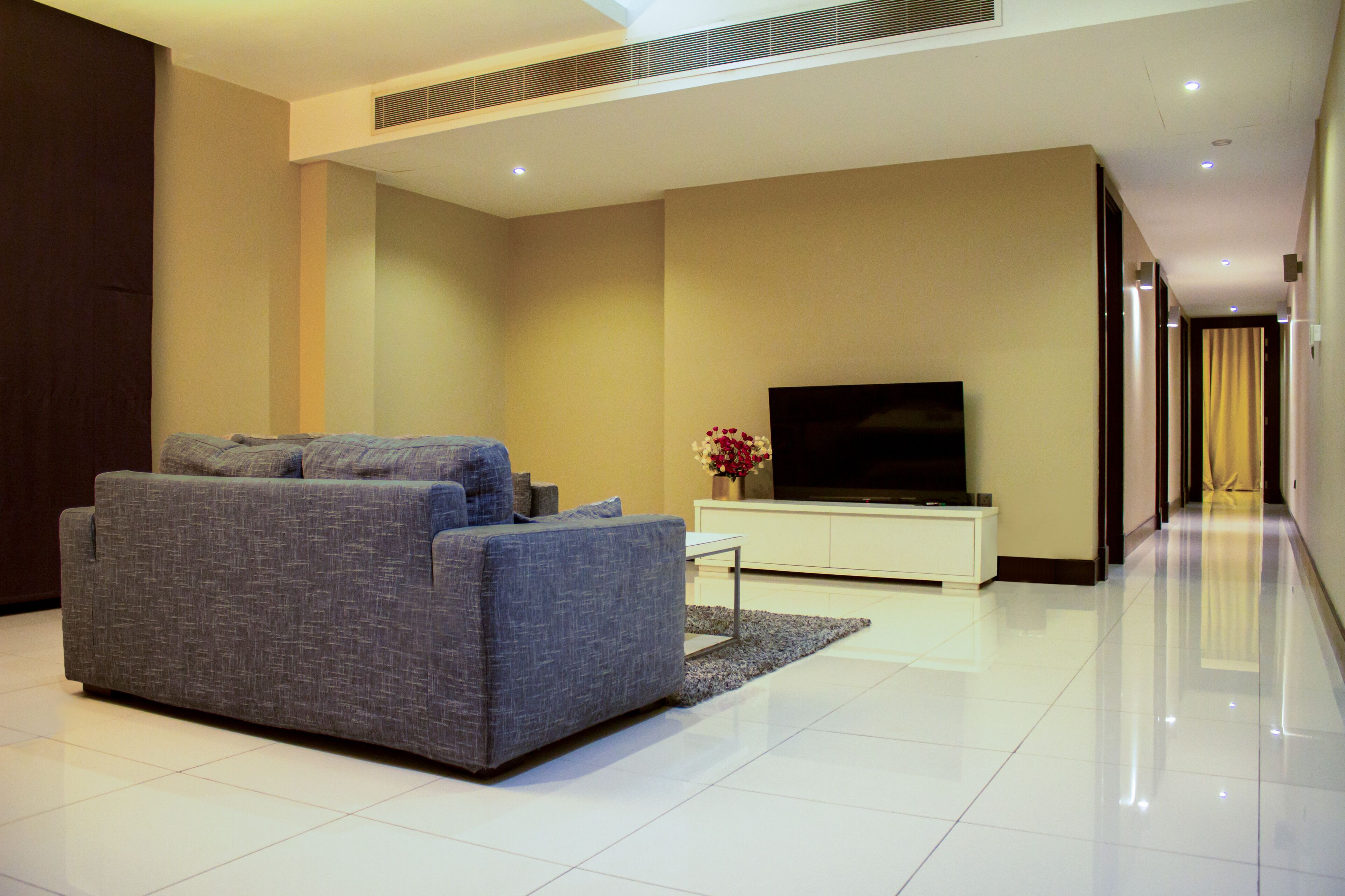 A modern living room with a grey sofa, a flat-screen TV, and a white entertainment unit.