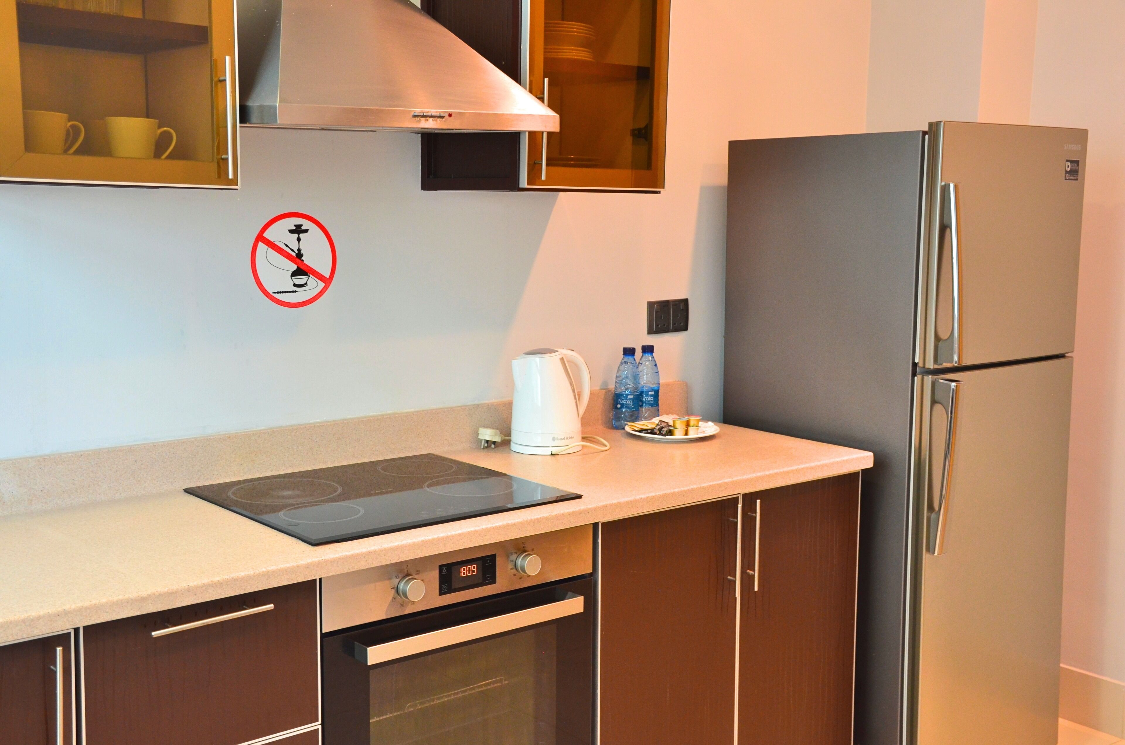 A kitchen with a built-in oven, a stainless steel refrigerator, and a coffee maker.