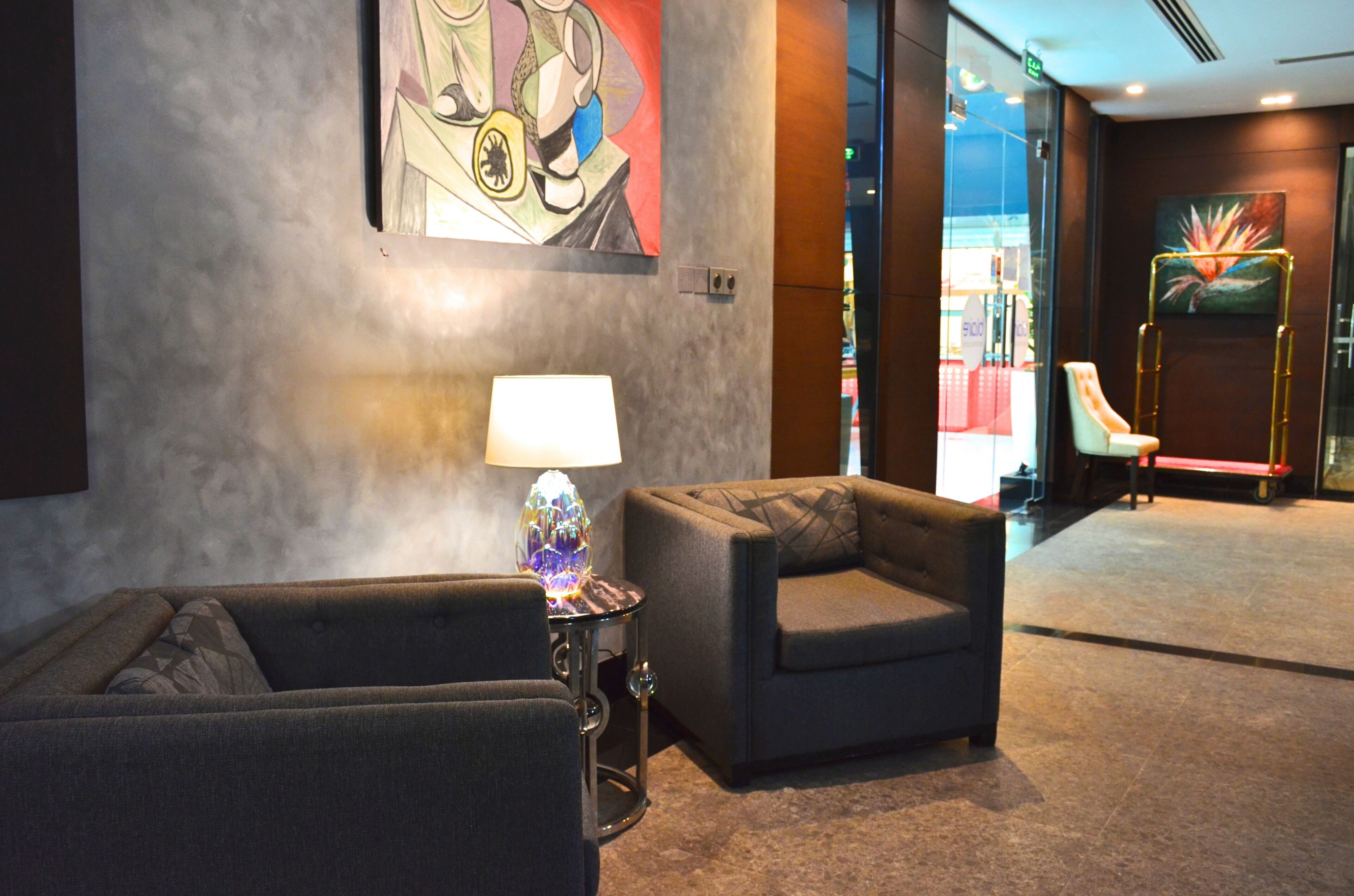 A modern lobby with two armchairs, a floor lamp, and abstract art on the walls.