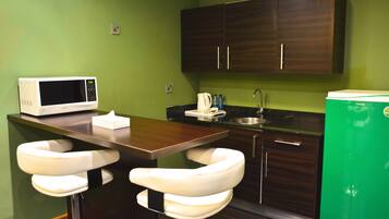 Una cocina compacta equipada con microondas, cafetera y dos taburetes de bar.