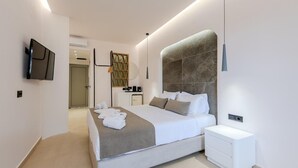 Una habitación de hotel moderna con una cama grande, una mesita de noche, un televisor montado en la pared y un pequeño escritorio con una silla.