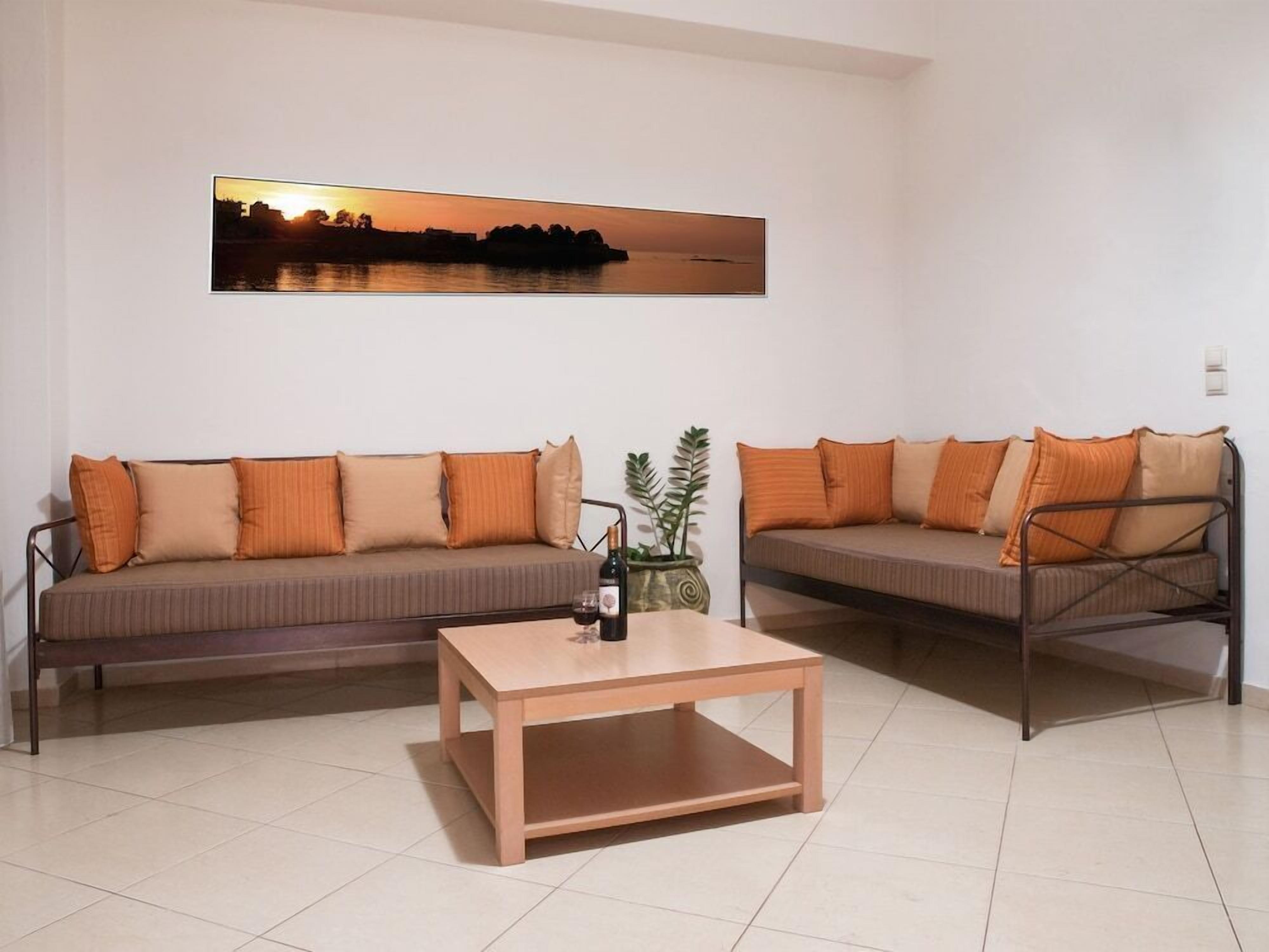 Ein Wohnzimmer mit zwei Sofas, einem Couchtisch und einem Gemälde, das einen Sonnenuntergang über dem Wasser zeigt.