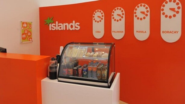 A storefront with a red wall and a glass display case filled with snacks. - Islands Stay Hotels Uptown (Cebu)