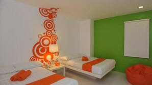 A hotel room with two beds, a green accent wall, and a bean bag chair. - Islands Stay Hotels Uptown (Cebu)