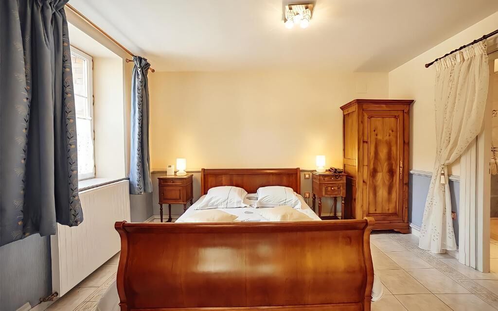 A bedroom with a wooden bed, bedside tables, a wardrobe, and a window with curtains.