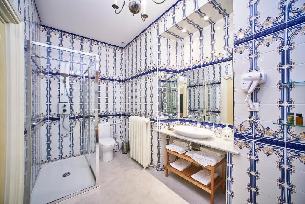 A bathroom with a shower, toilet, and sink, featuring blue and white patterned tiles.