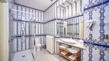 A bathroom with a shower, toilet, and sink, featuring blue and white patterned tiles.