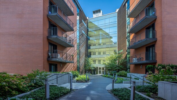A modern building with a central glass facade, surrounded by brick structures with balconies. - FriendHouse Apartments - City Center (Kraków)
