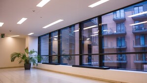 A spacious hallway with large windows, a potted plant, and a tiled floor. - FriendHouse Apartments - City Center (Kraków)