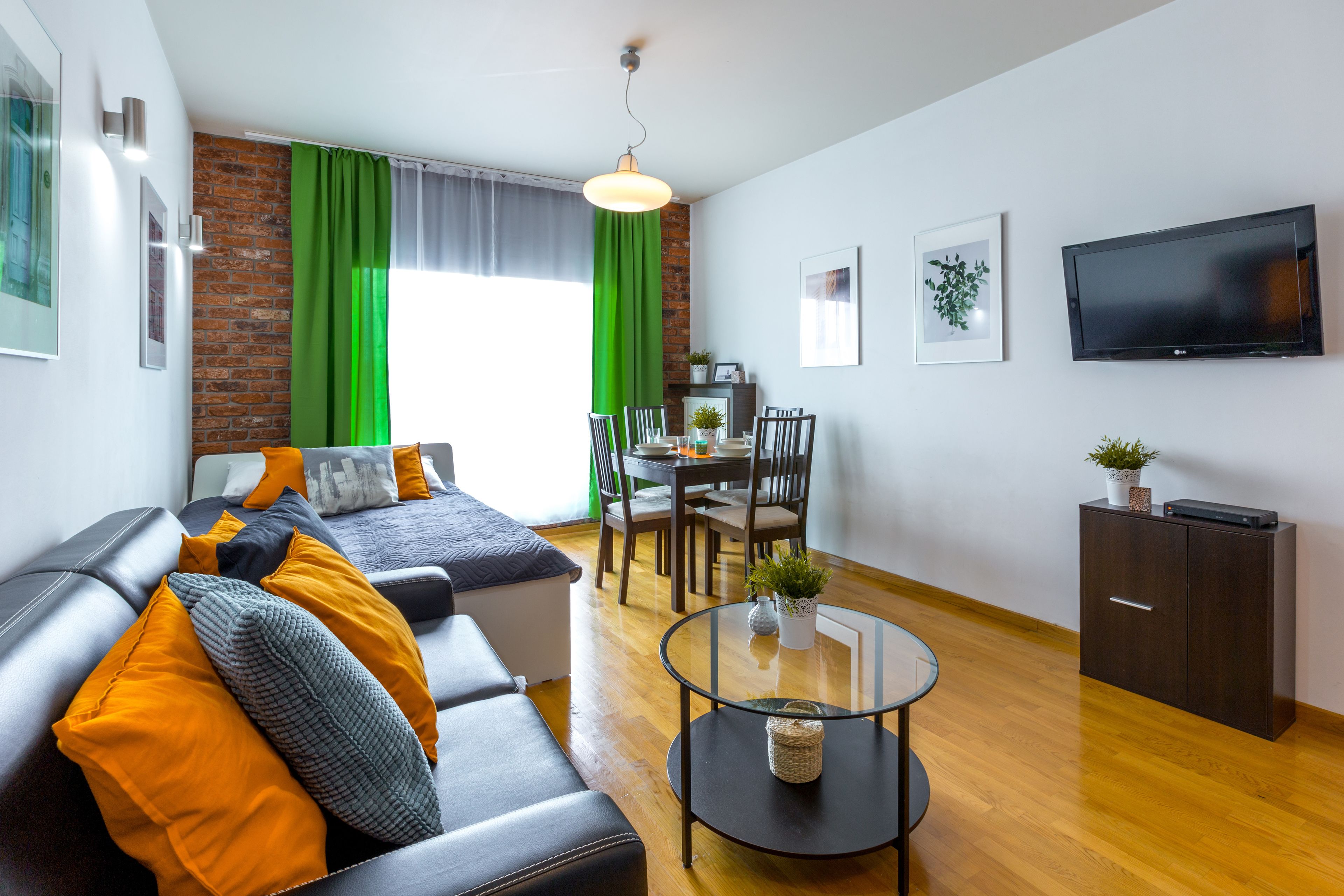A modern living room with a leather sofa, a glass coffee table, and a dining area with a table and chairs.
