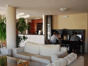 A living room with a sofa, a coffee table, and a fireplace area where two people are seated.
