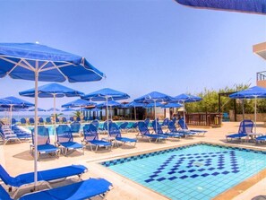 A pool area with blue umbrellas and lounge chairs.