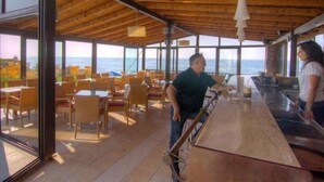 A restaurant with a wooden ceiling, large windows, and a bar area. - Krini Beach Hotel (Rethymno)