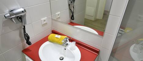 A bathroom with a white sink, red countertop, and a hairdryer mounted on the wall.