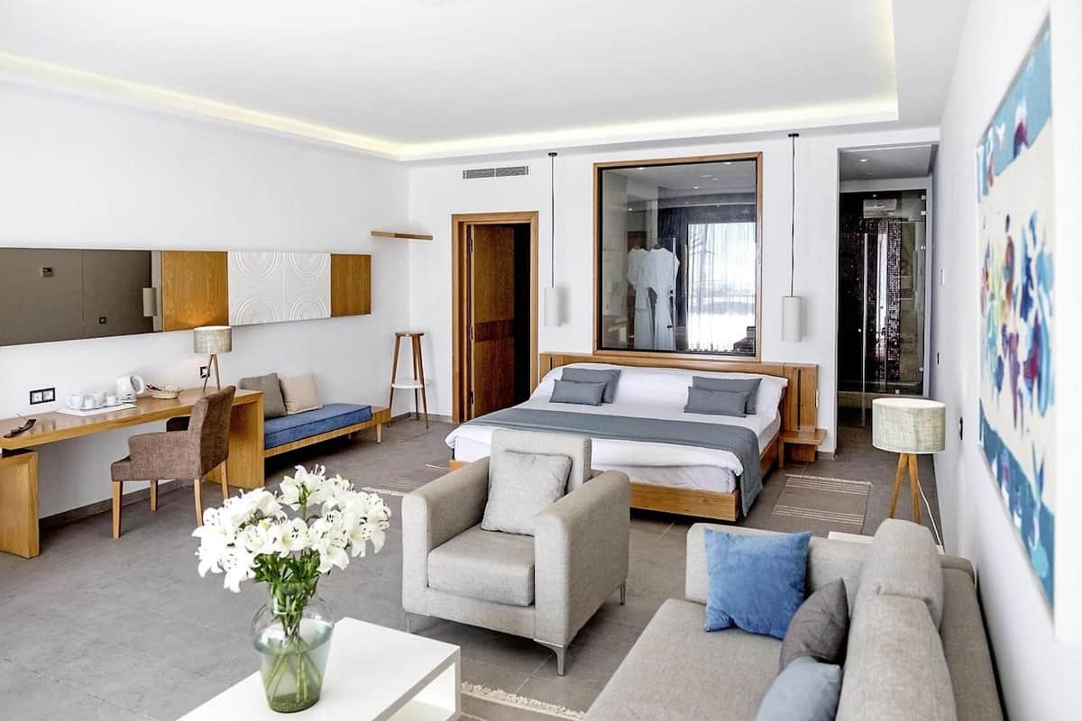Une chambre d’hôtel moderne, dotée d’un grand lit, d’un bureau, d’un canapé et d’un fauteuil.