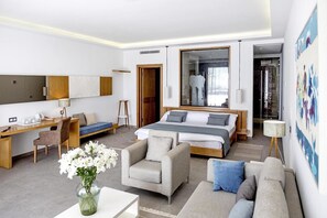 Ein modernes Hotelzimmer mit einem großen Bett, einem Schreibtisch, einer Sitzecke und einem Sessel.