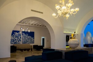 Un vestíbulo con candelabro, obra de arte azul y una escultura esférica.