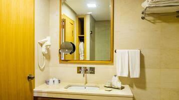 Un baño con lavamanos, espejo, toallero y una puerta de madera.