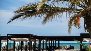Een strandlounge met parasols en ligbedden, met uitzicht op zee.