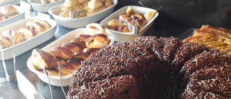 A buffet with various baked goods including a large chocolate cake with sprinkles.